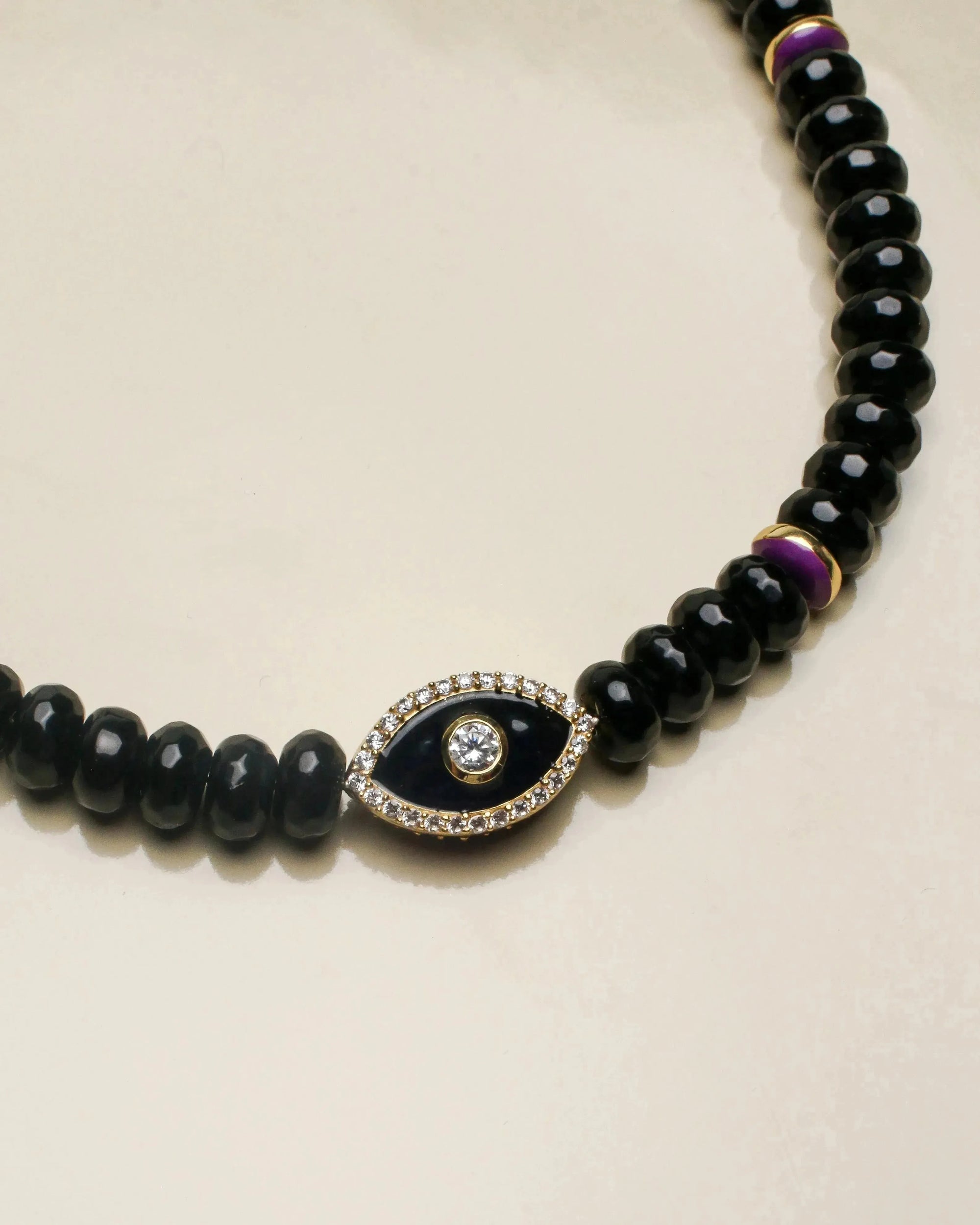 Close-up view of the Stella necklace showcasing the smooth black onyx beads with a central evil eye charm, adding a protective and stylish element.