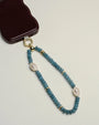 Apatite beaded Stella wristlet with white evil eye-shaped charms, attached to a phone case for a stylish touch of energy protection and clarity.