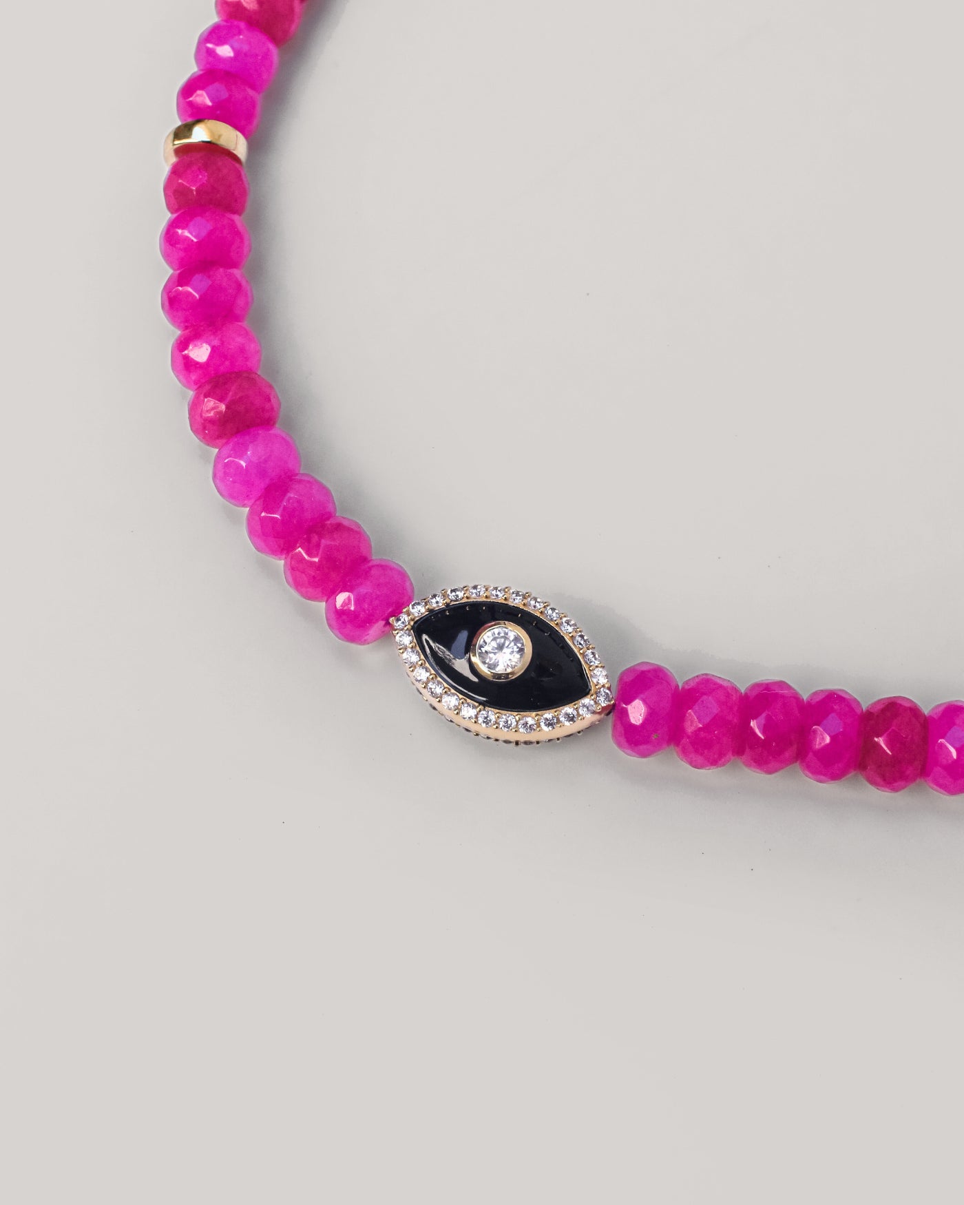 Close-up of a Stella phone wristlet in passionate pink quartz, featuring an intricate evil eye charm for stylish protection and positive energy. 