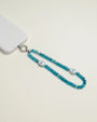 Stella phone wristlet crafted with turquoise beads and adorned with an elegant evil eye charm, attached to a white phone for a stylish touch.