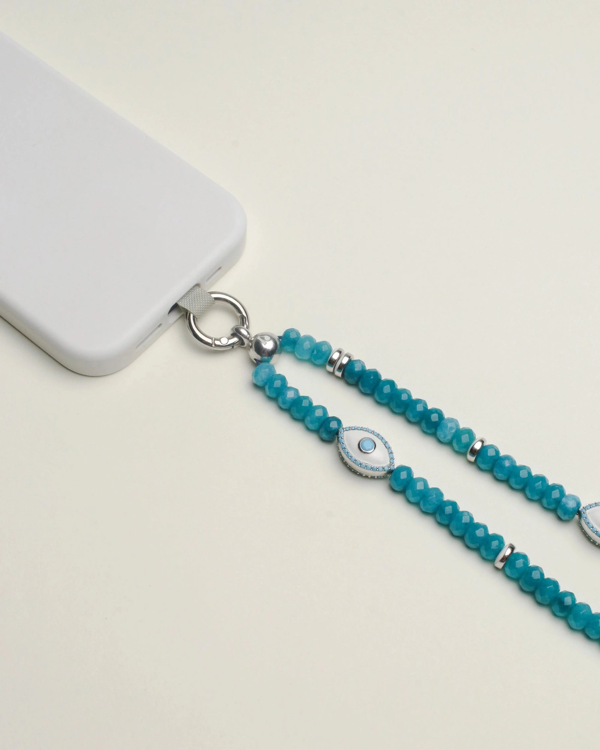 Close-up of the Stella phone wristlet in turquoise quartz with an intricate evil eye charm, elegantly looped for easy attachment.