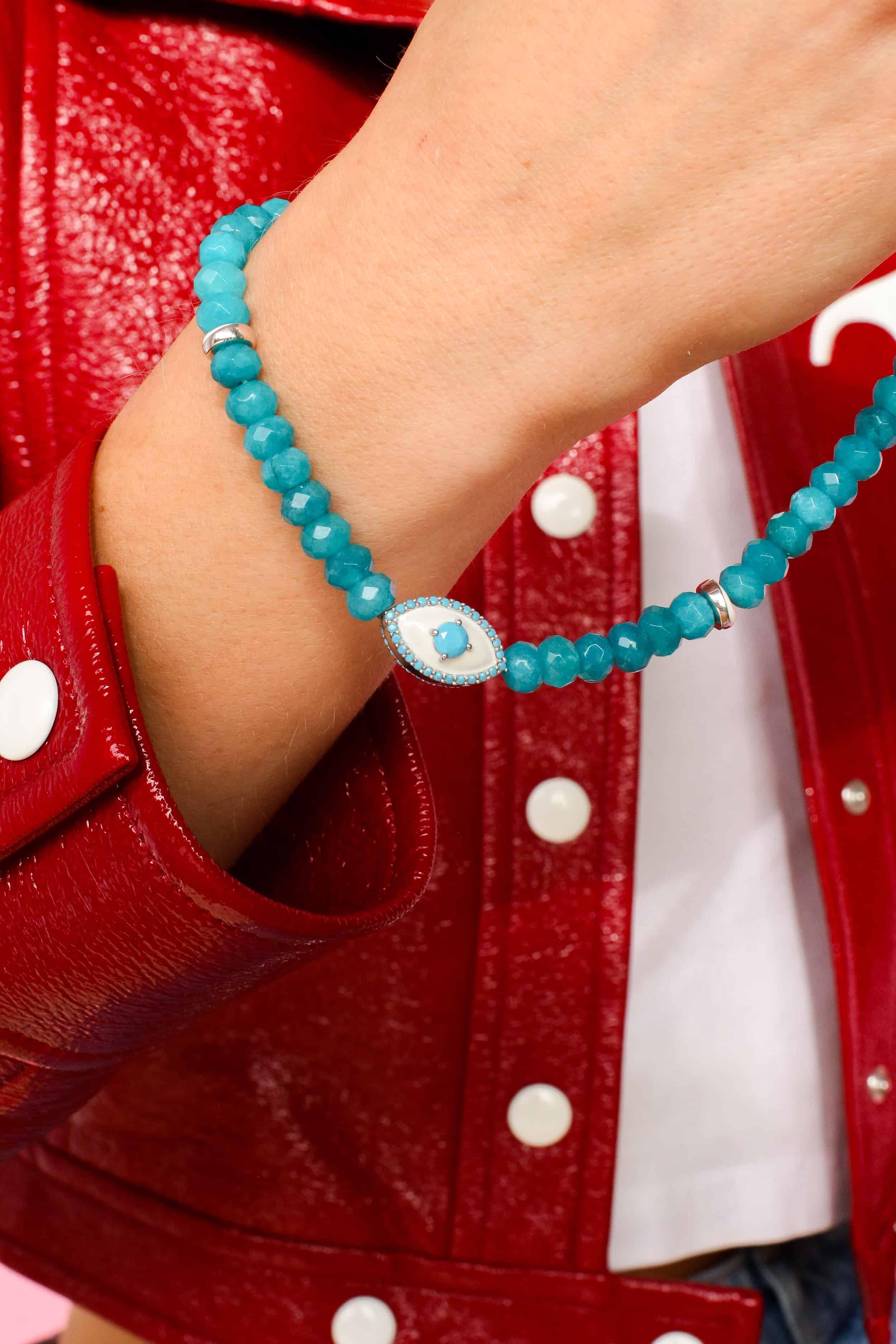 a close-up of a turquoise quartz phone strap around a woman's wrist