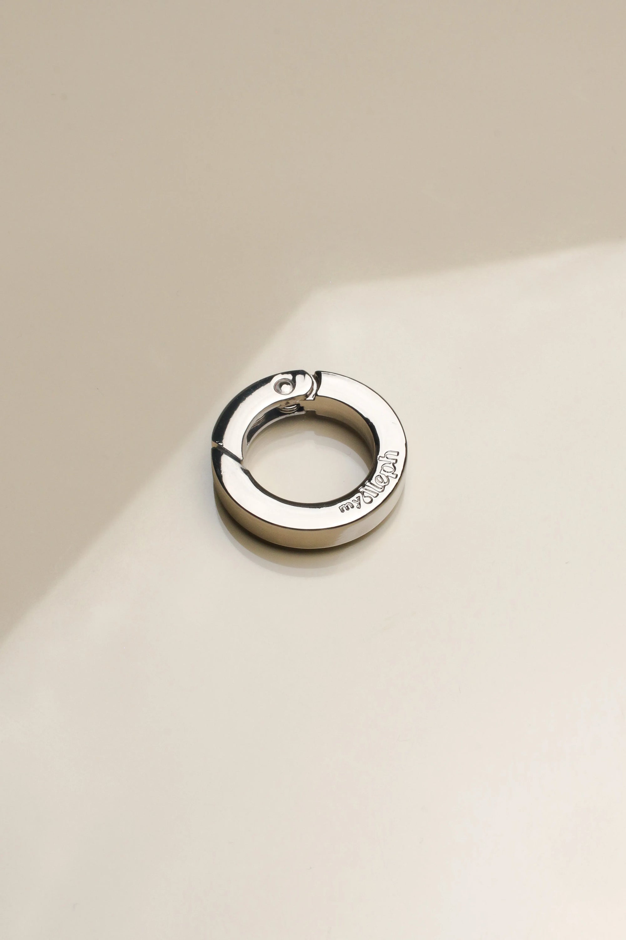 Detailed image of 'The Ring' accessory in silver, highlighting its smooth finish and functional clasp, perfect for integrating with phone wristlets and charms.