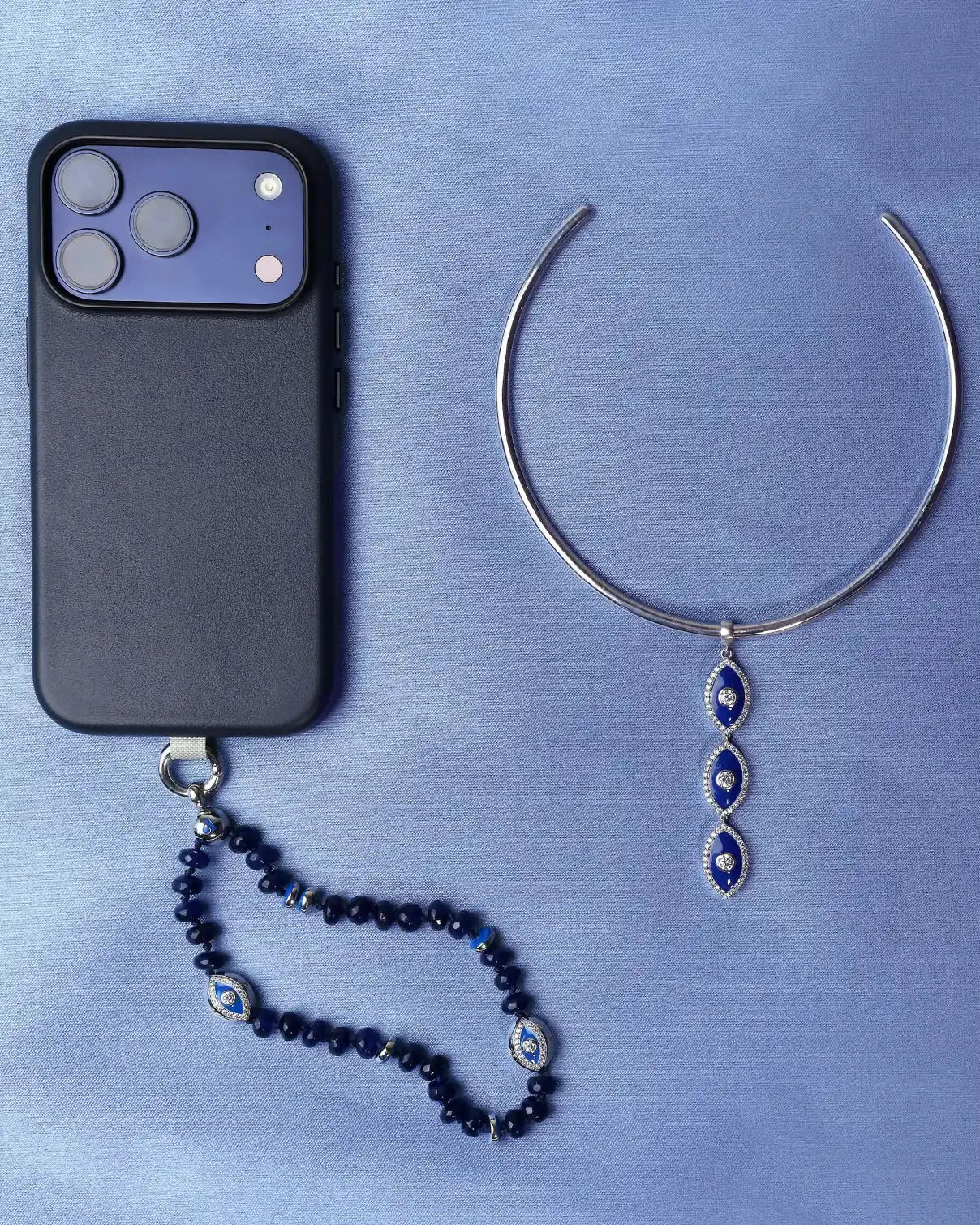 Flat lay of the full Winter Collection Gift Set with the choker and phone charm arranged together next to a black phone case.