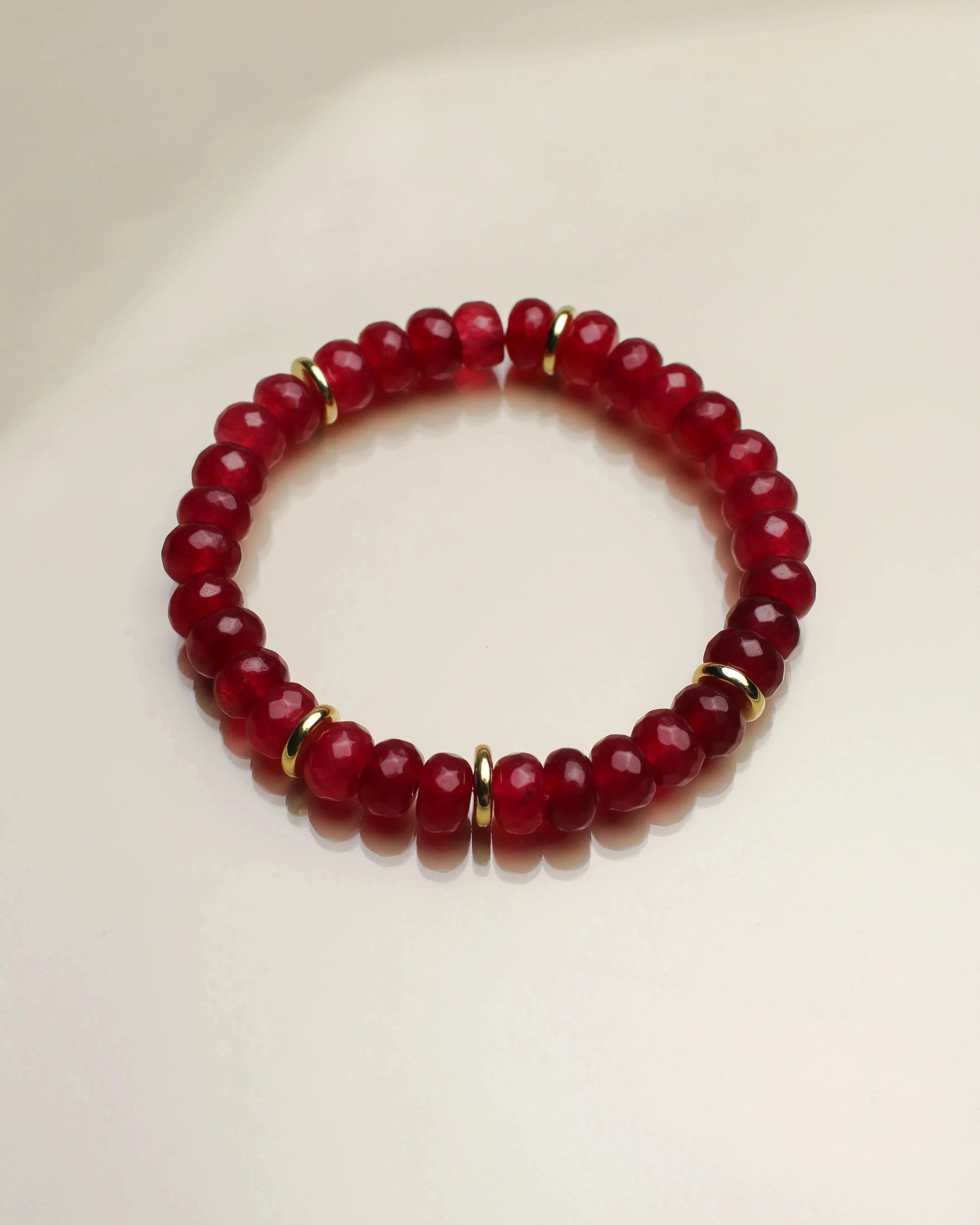 Close-up of a single Zoe cherry quartz bracelet, capturing the vivid red tones and intricate gold detailing.