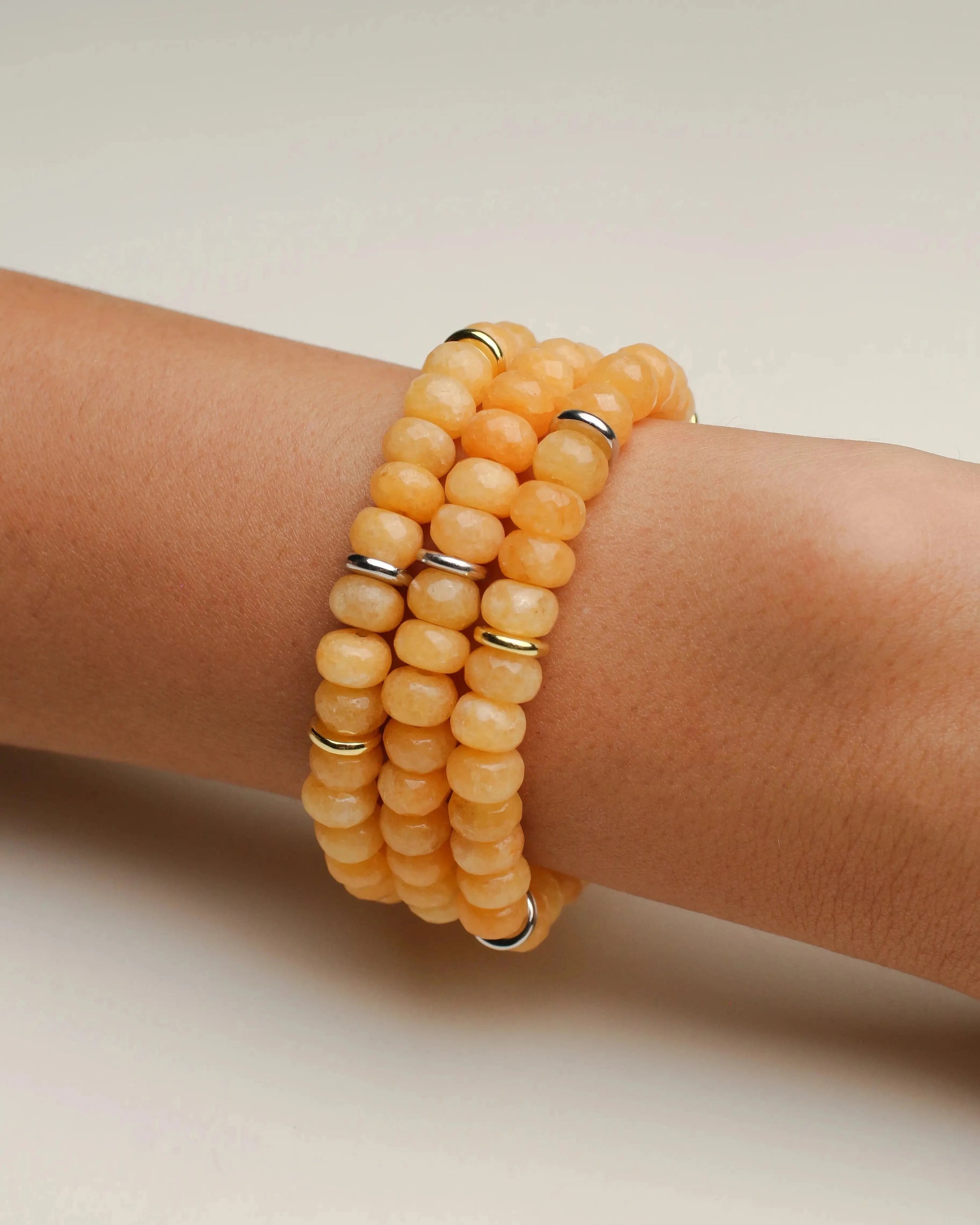 Set of three Zoe bracelets featuring vibrant tangerine quartz beads stacked on a wrist, showcasing a radiant and cheerful design.