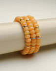 Close-up view of three Zoe tangerine quartz bracelets stacked on a display, emphasizing the bright and sunny hues.