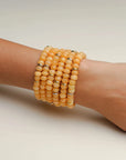 Zoe tangerine quartz bracelets stacked together on a display, highlighting their smooth, polished finish and warm tones.