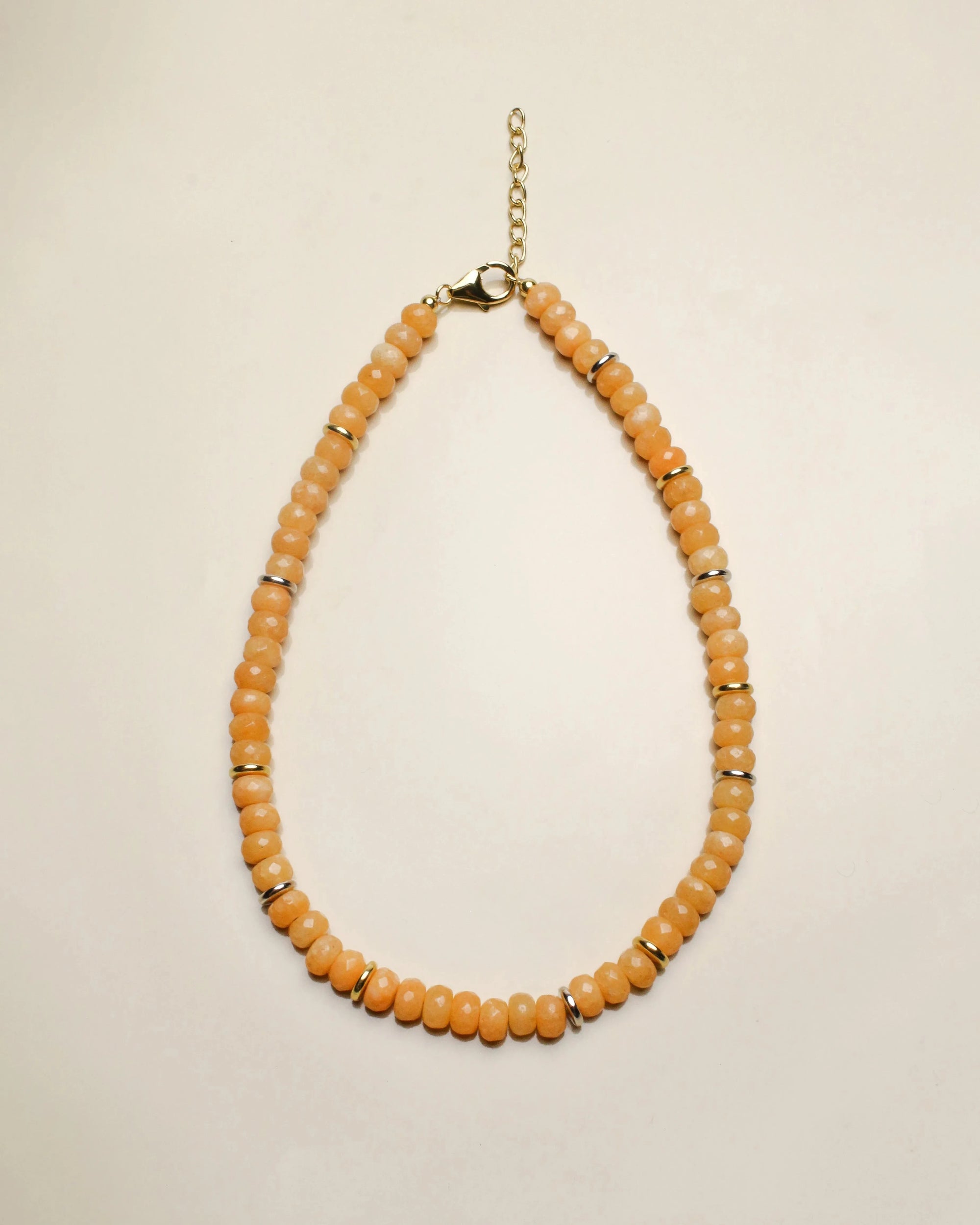 The Zoe necklace featuring vibrant tangerine quartz beads, arranged in a graduated design with a gold chain clasp