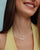 Model layering the Julianna Necklace in Moonstone with other pieces, styled with a yellow top for a warm, elevated look.