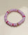 Close-up view of a single valerie lavender bracelet from the set of three, highlighting its soft purple beads with pink and gold dividers arranged in a circular layout.